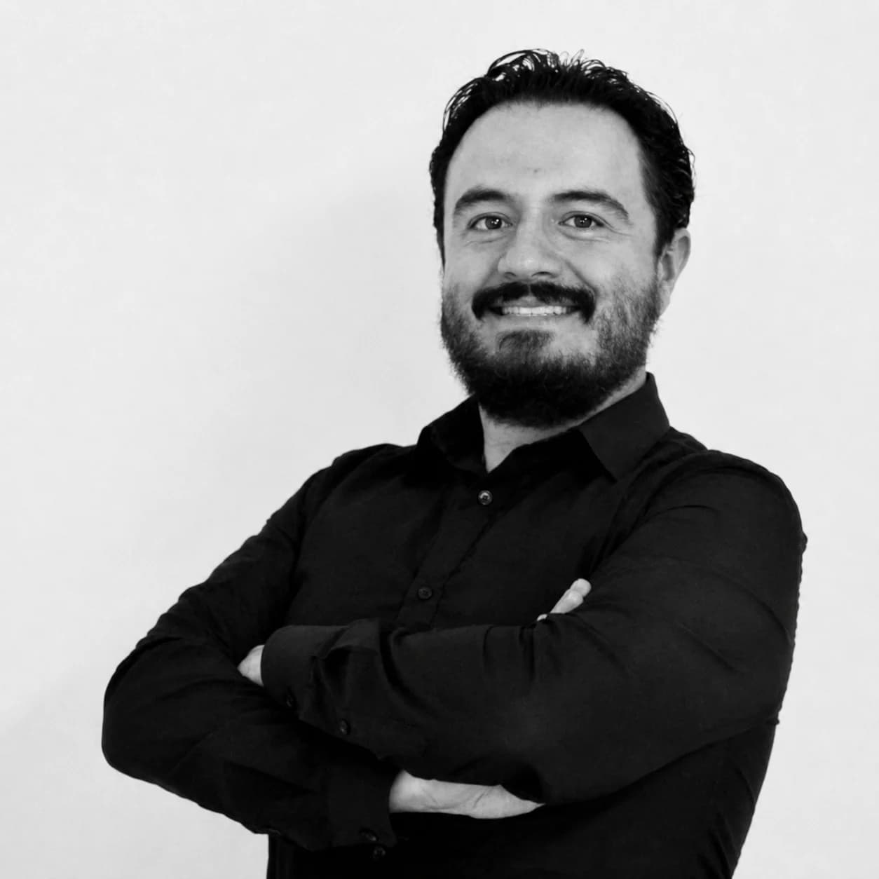 Black-and-white portrait of Jorge Gasca smiling with his arms crossed